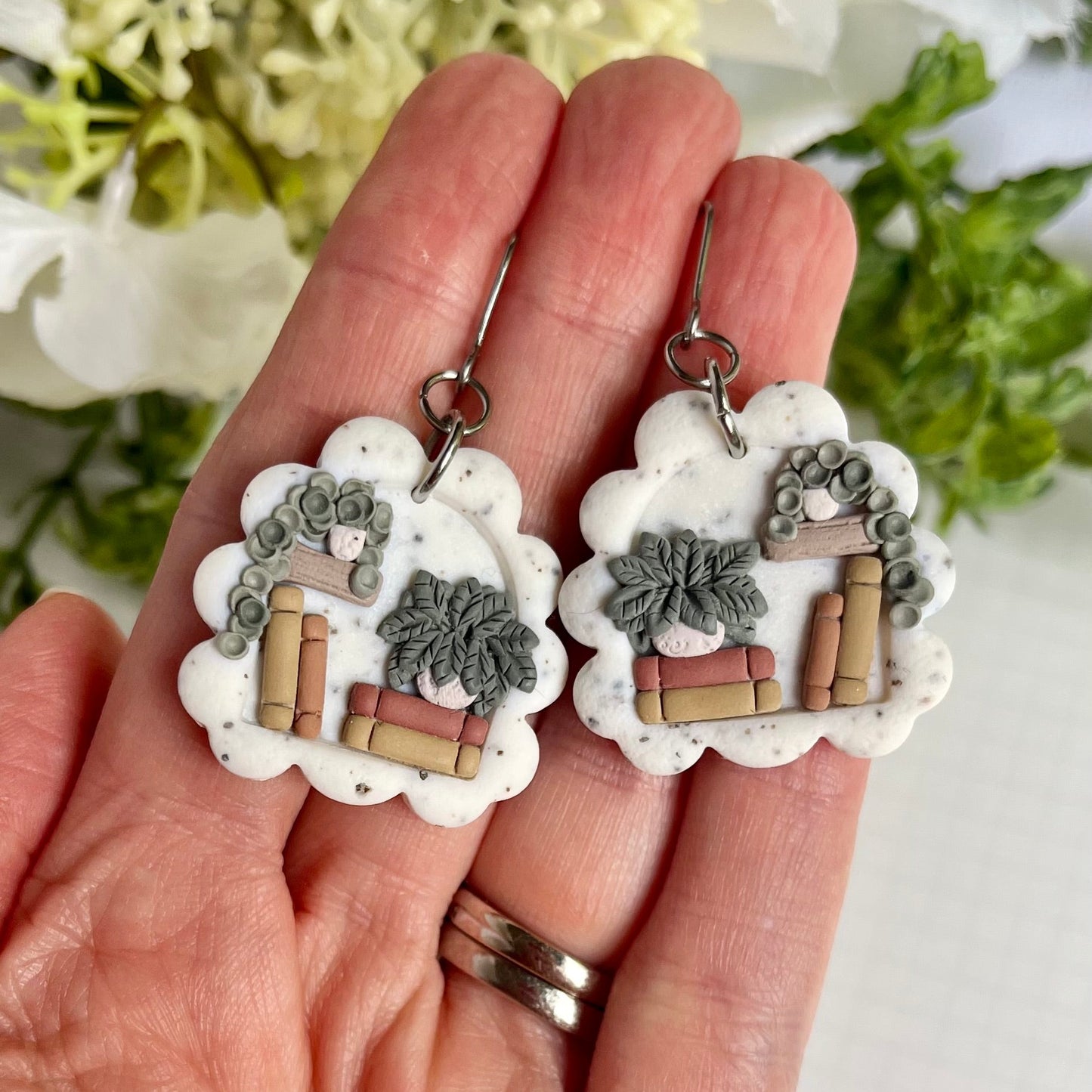 Pair of bookshelf earrings with potted plants set on a white speckled background