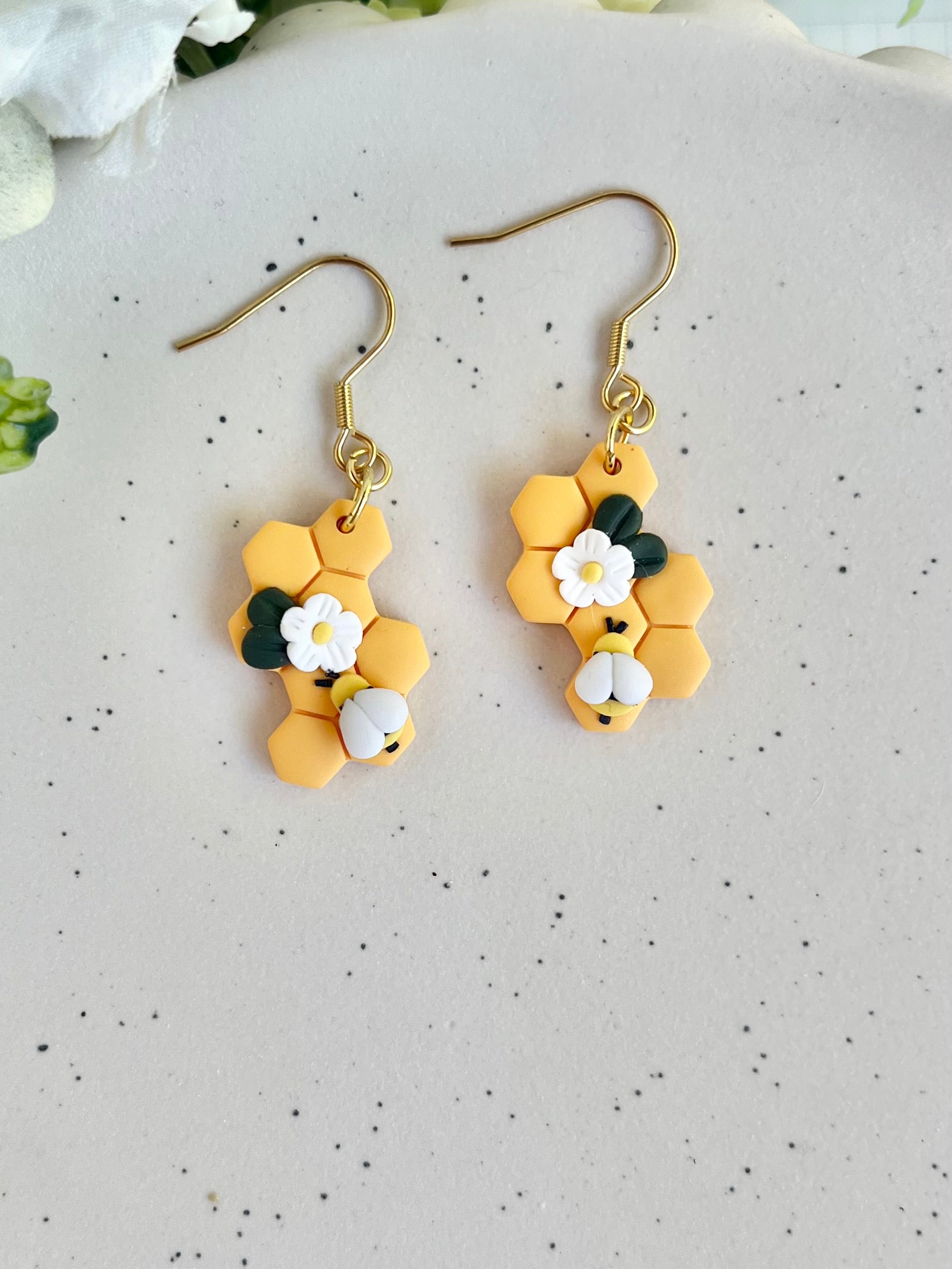 Hexagonal earrings with floral designs on a speckled surface