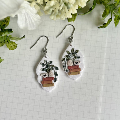 Pair of earrings with plant designs on a grid background