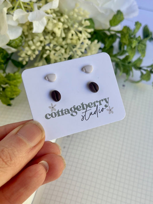 Pair of black earrings on a 'cottageberry studio' card held by a hand with a floral background.