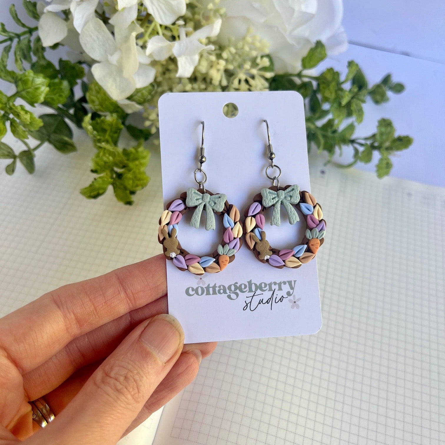 Colorful hoop earrings on a card held by a hand with a floral background
